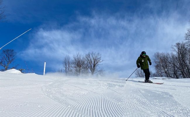 skier on groomed trail blue sky