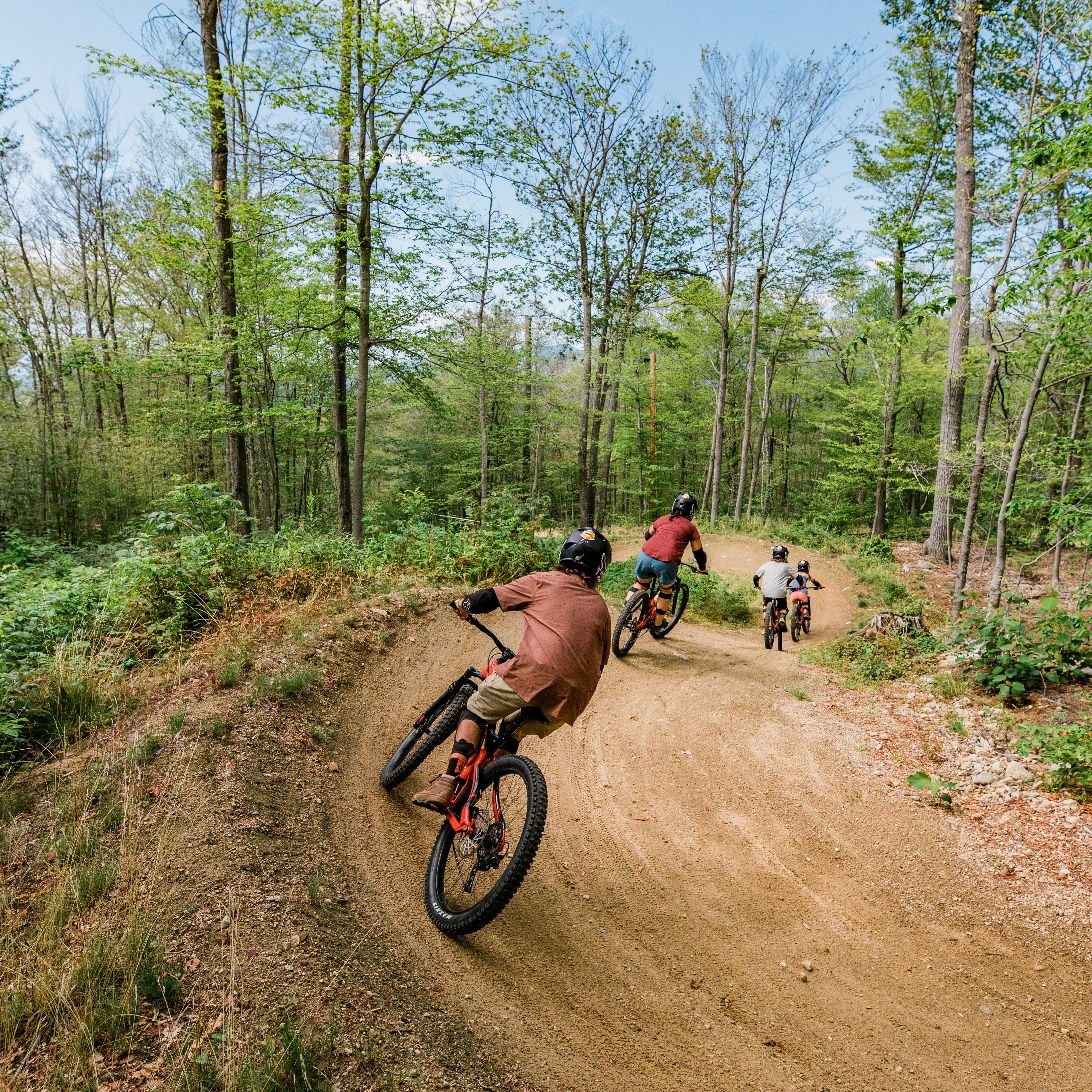 Bike Park Family from behind going around curve on flow trail