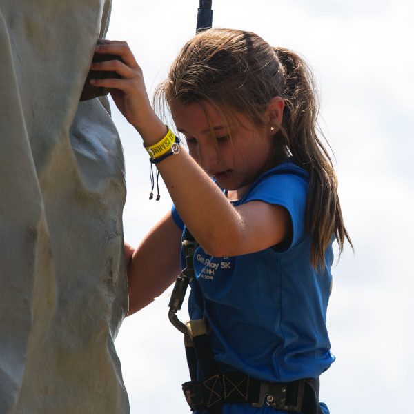 closeup of child in blue shirt on the climbing wall